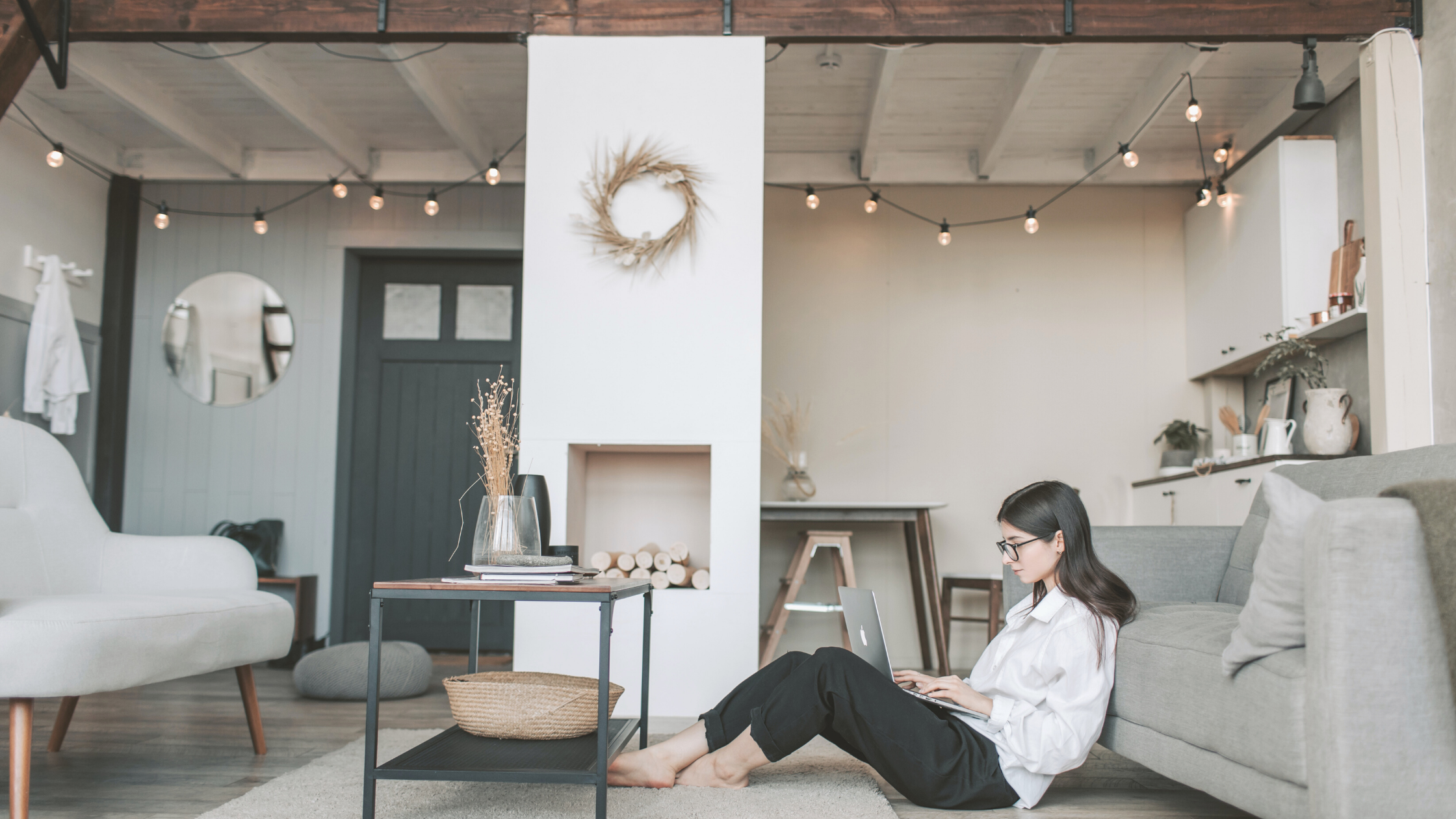 girl sitting on the floor in front of a grey couch with her laptop on her lap